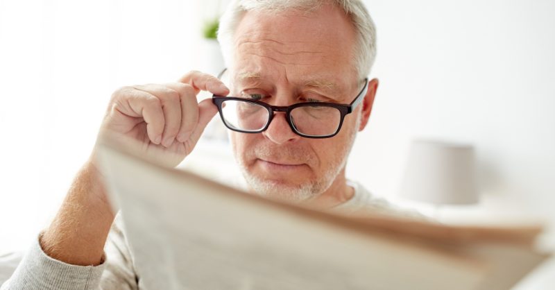 Man with glasses reading newspaper