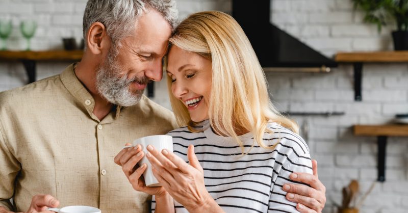 An older couple hugging and holding a cup